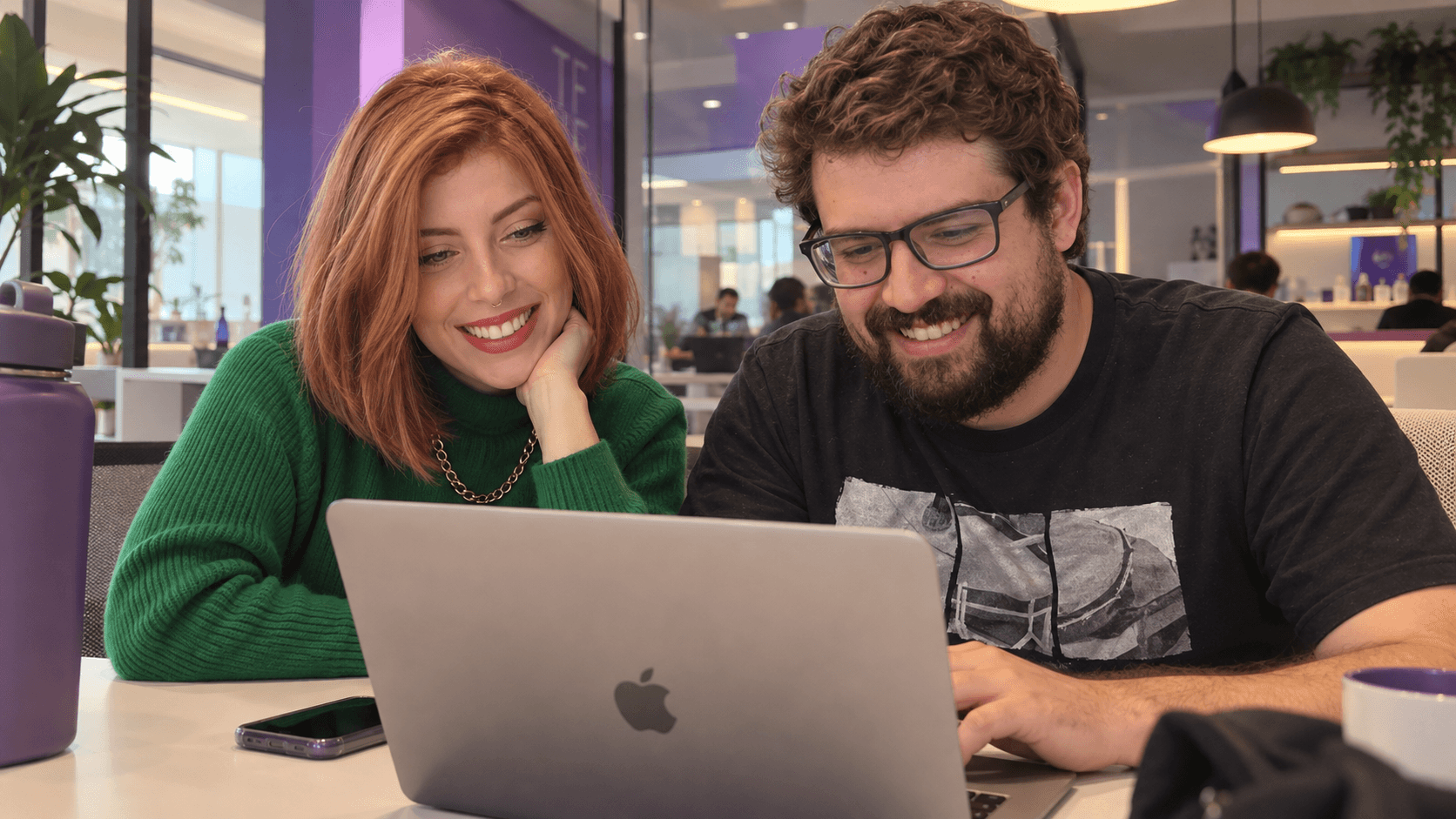 dupla da squad rindo diante de um notebook no escritório